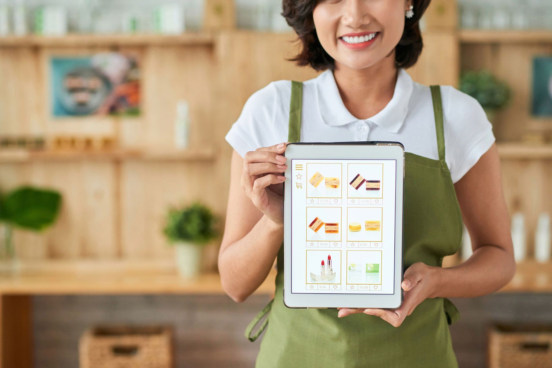 A woman in an apron is holding a tablet in her hands.
