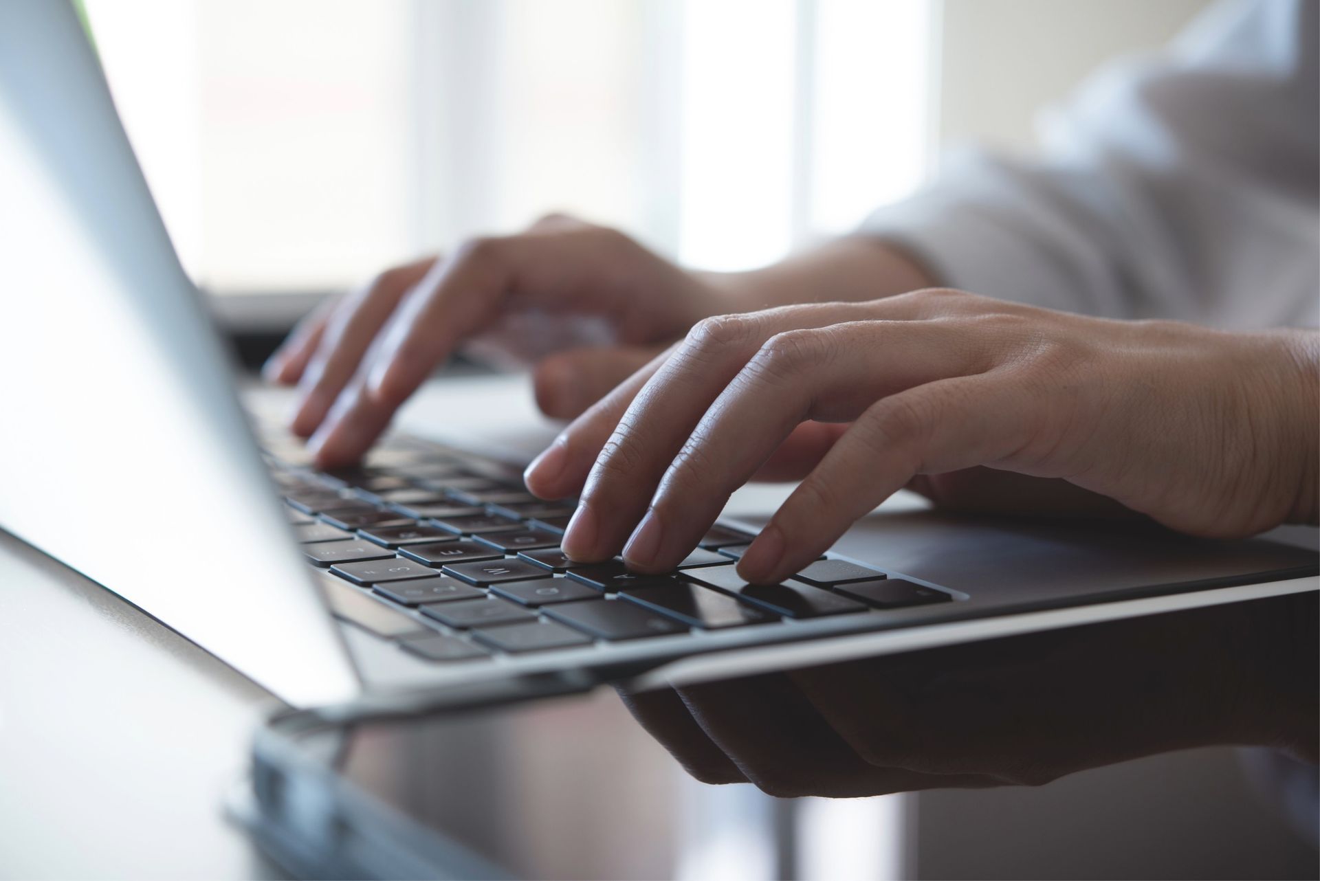 Hands typing on a laptop keyboard; focus on hands and keys.