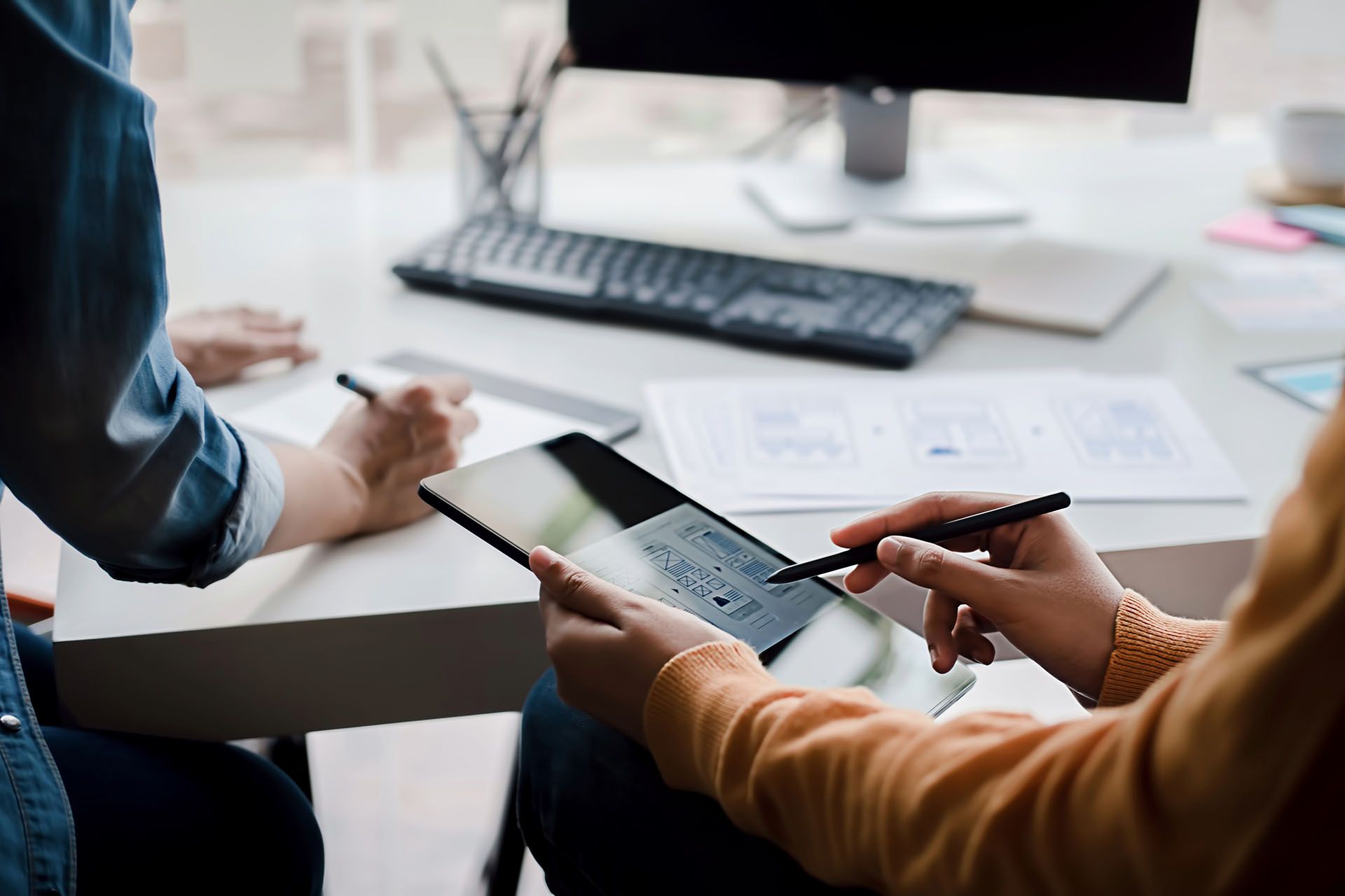 A man and a woman are sitting at a table using a tablet computer.