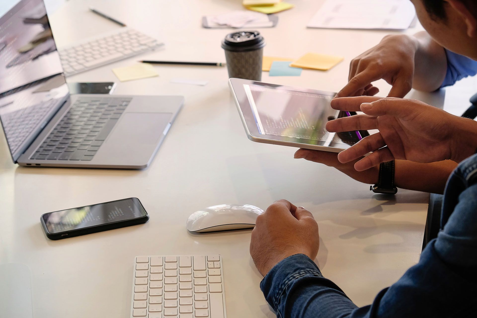 A group of people are sitting at a table looking at a tablet.