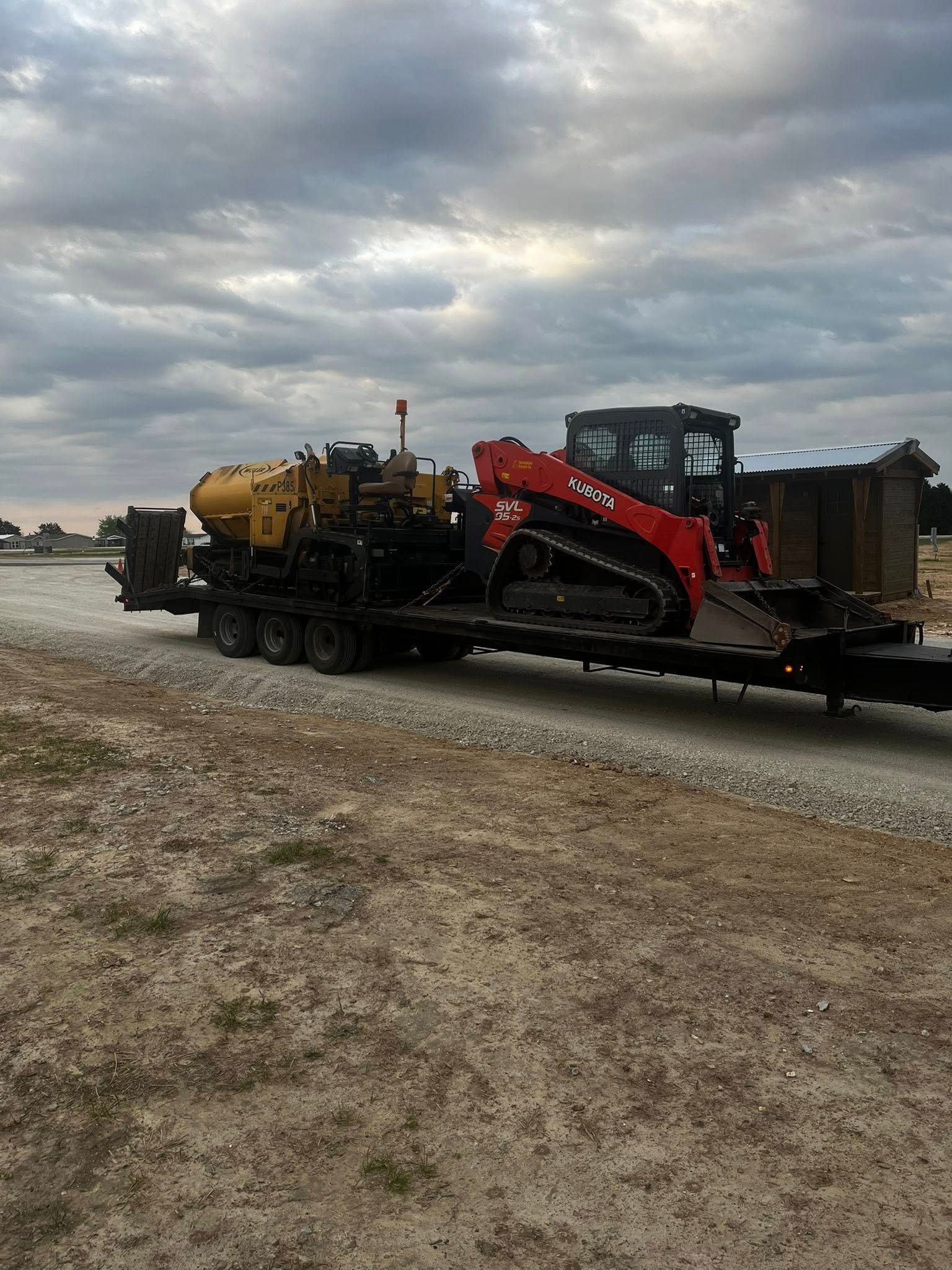 A red and yellow tractor is being transported on a trailer.
