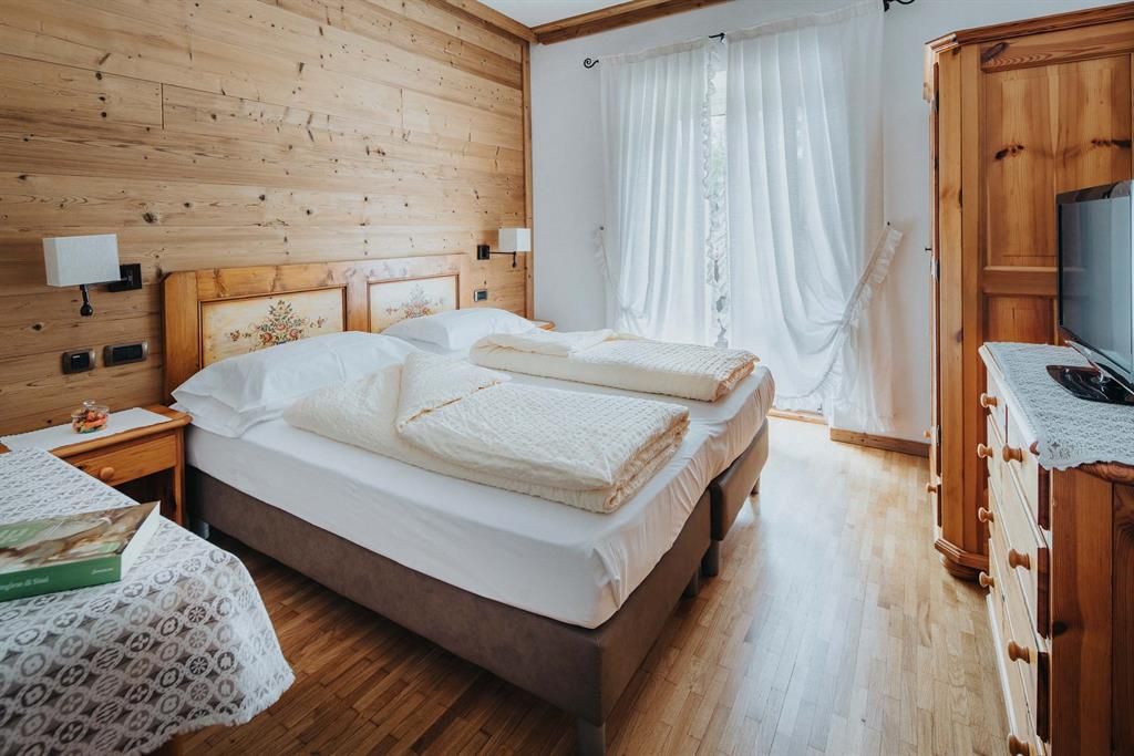 Ein Hotelzimmer mit zwei Betten, einer Kommode und einem Fernseher.