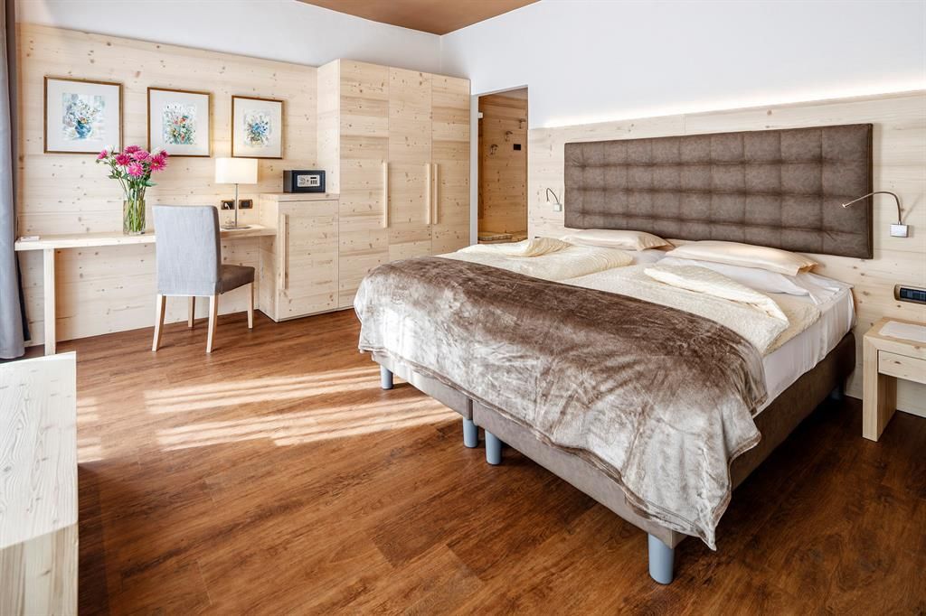 Ein Hotelzimmer mit großem Bett, Schreibtisch und Stuhl.