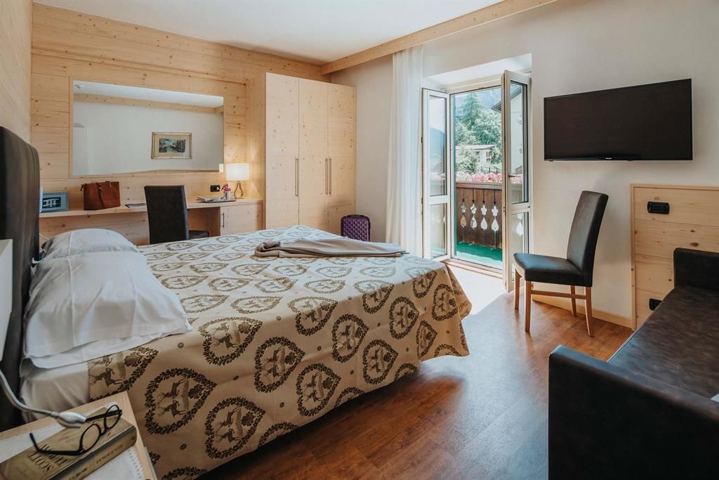 Ein Hotelzimmer mit großem Bett, Couch, Fernseher und Balkon.