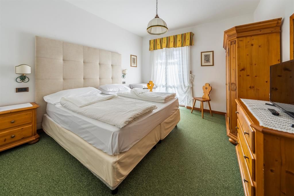 Ein Hotelzimmer mit zwei Betten, einer Kommode und einem Fernseher.