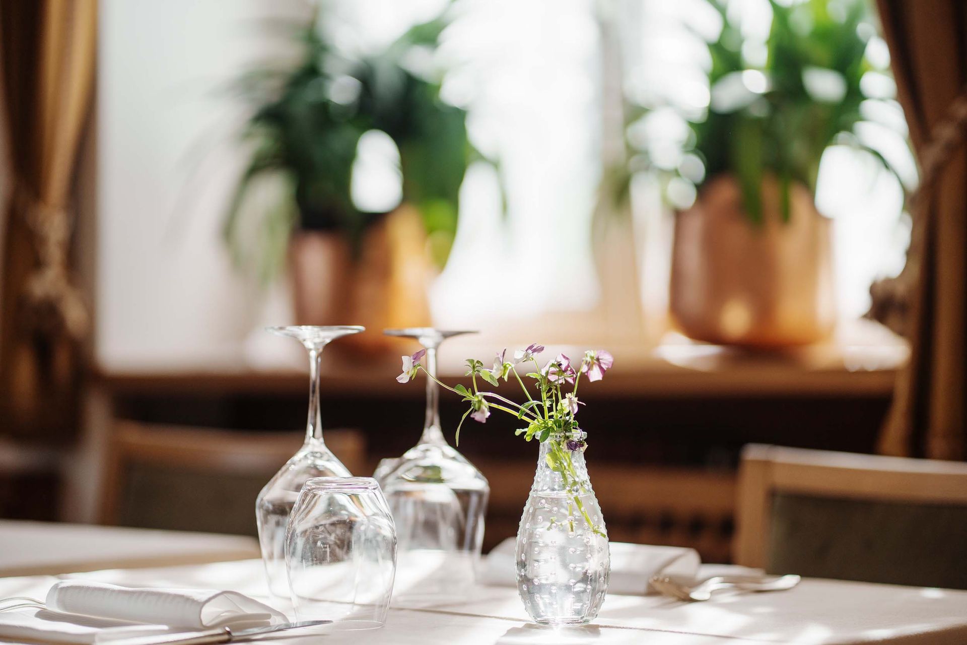 Ein Tisch mit Weingläsern und einer Vase mit Blumen darauf.