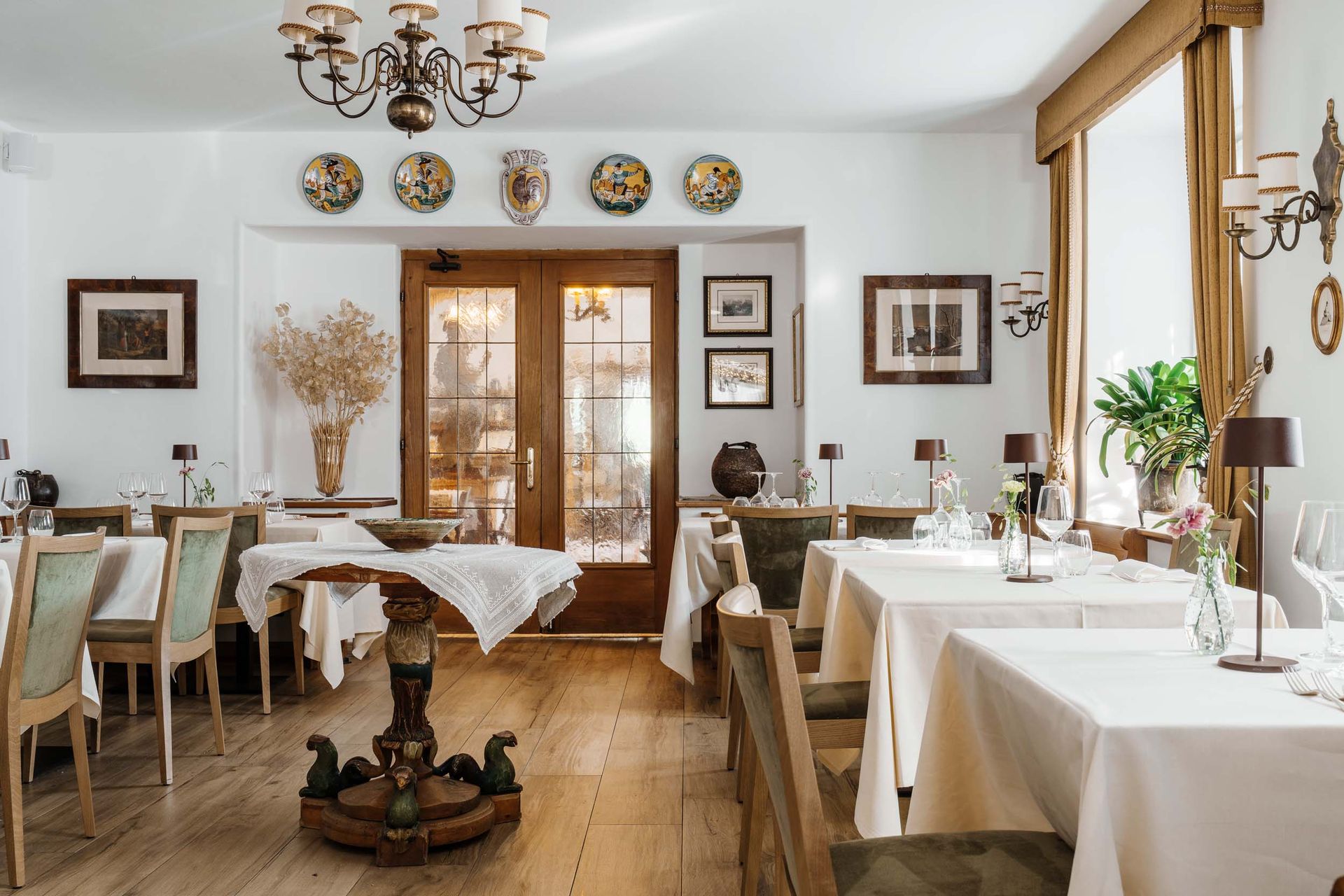 Ein Esszimmer mit Tischen und Stühlen und einem Kronleuchter, der von der Decke hängt.