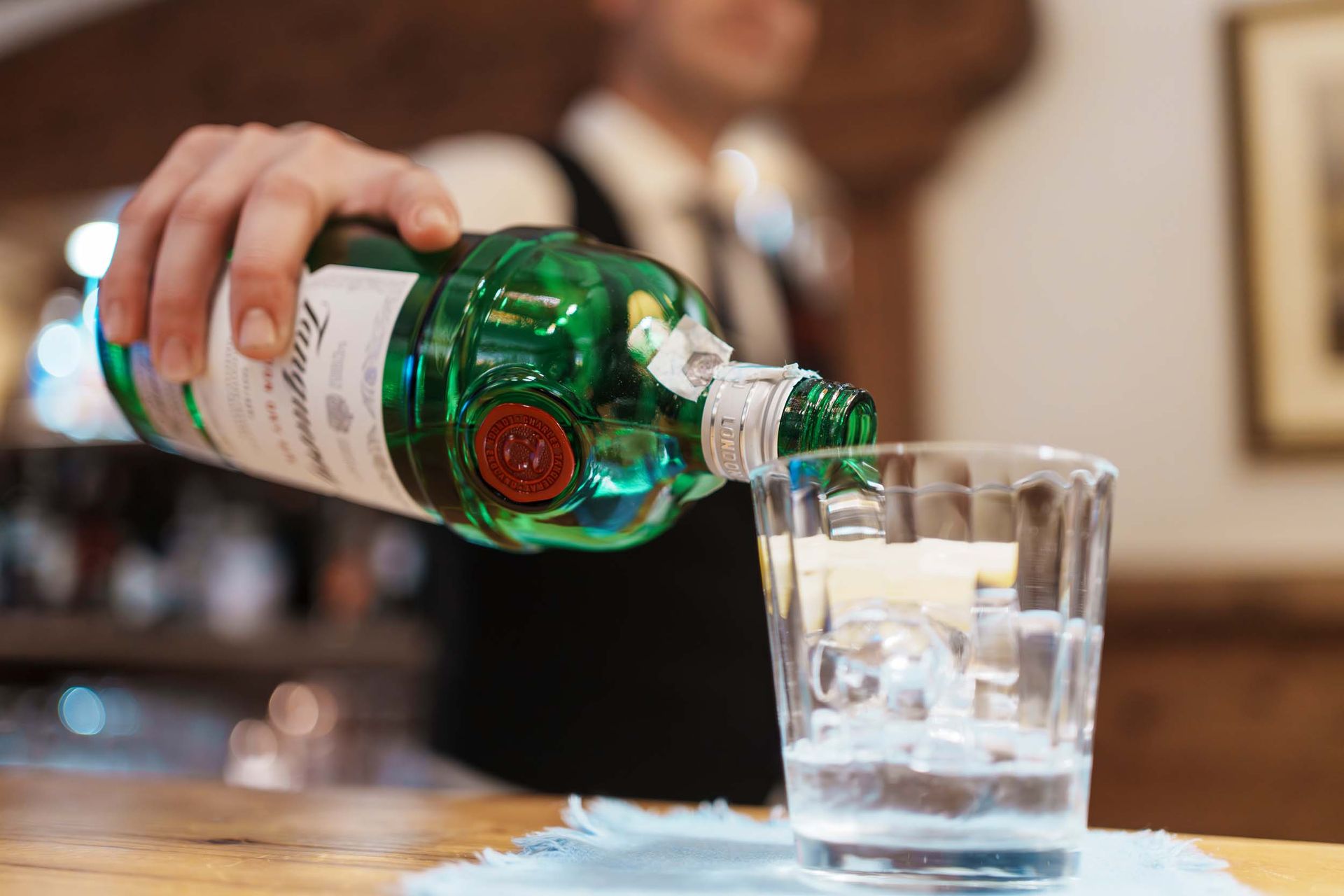 Ein Barkeeper gießt ein Getränk in ein Glas.