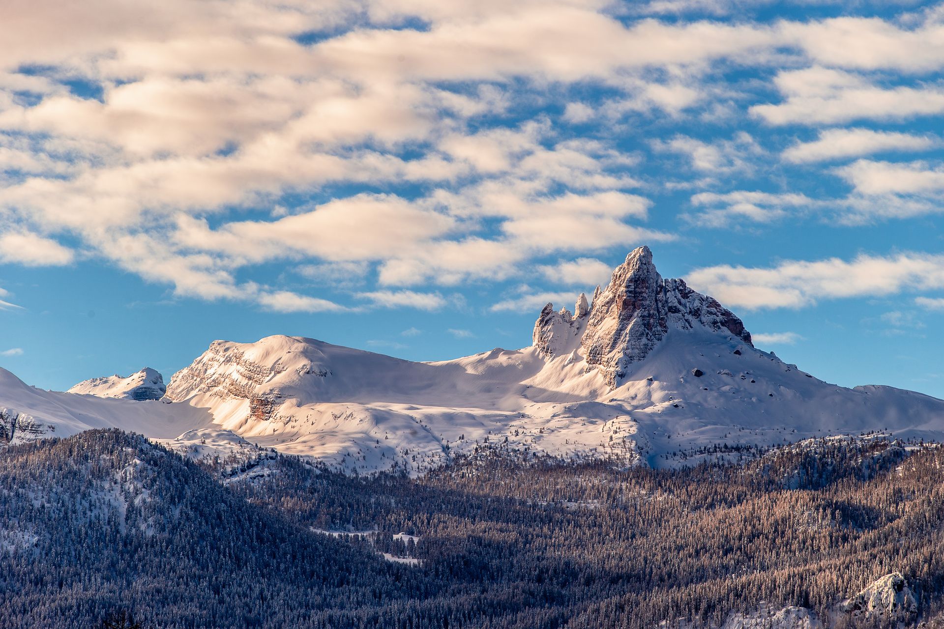 Ein schneebedeckter Berg mit blauem Himmel und Wolken im Hintergrund