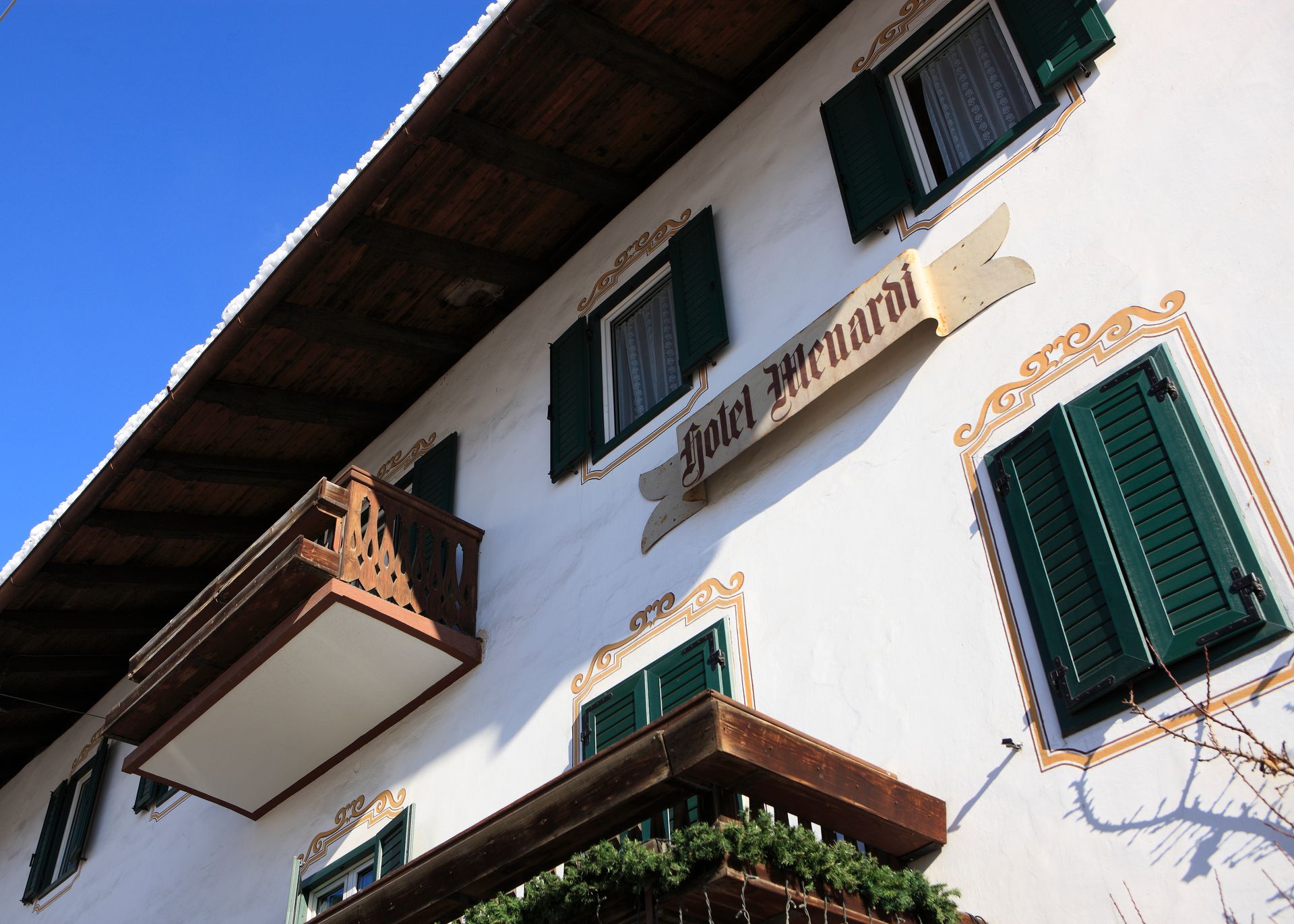 Hotel Menardi mit grünen Fensterläden und einem Schild mit der Aufschrift „Hotel Menardi“