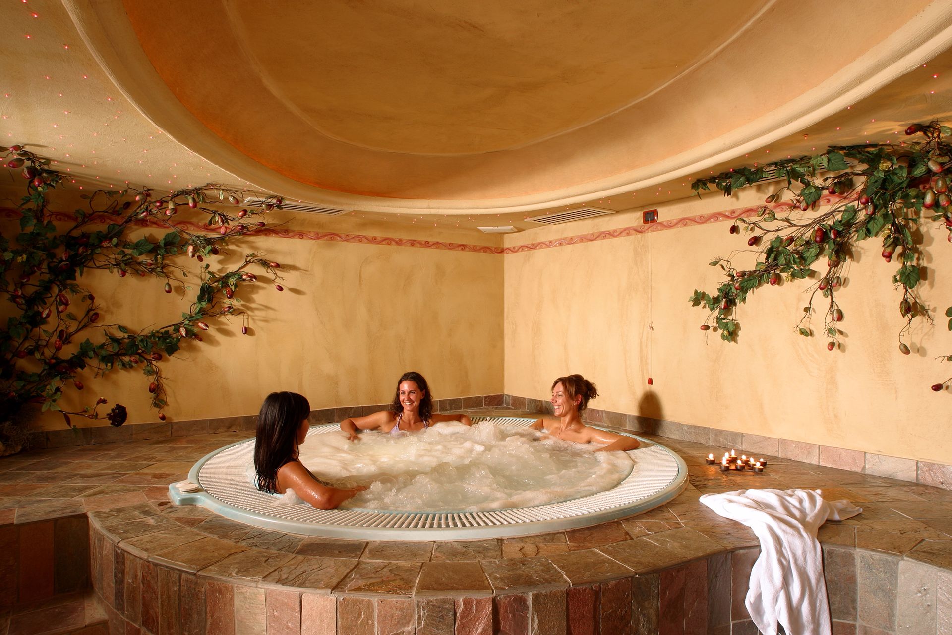 Drei Frauen sitzen in einem Whirlpool in einem Zimmer.