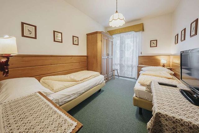 A hotel room with two beds and a flat screen tv.