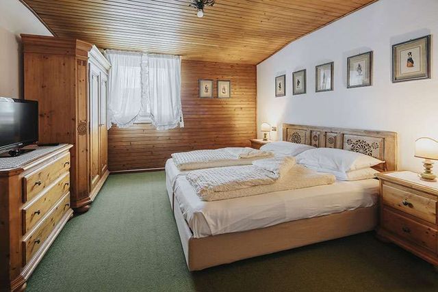 A bedroom with two beds , a dresser and a television.