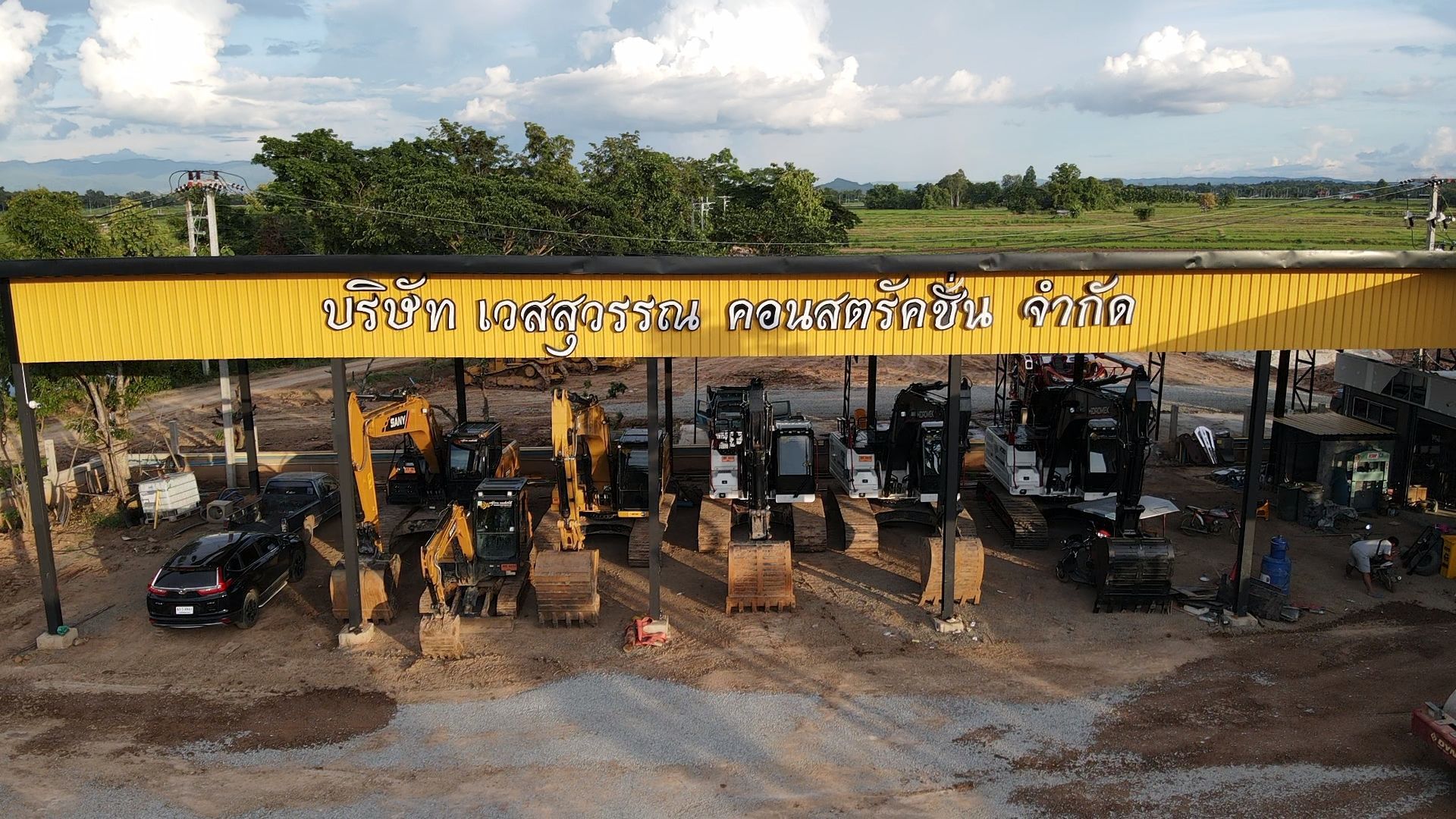 Yellow roadside canopy with parked motorcycles and a few people underneath, under a cloudy sky