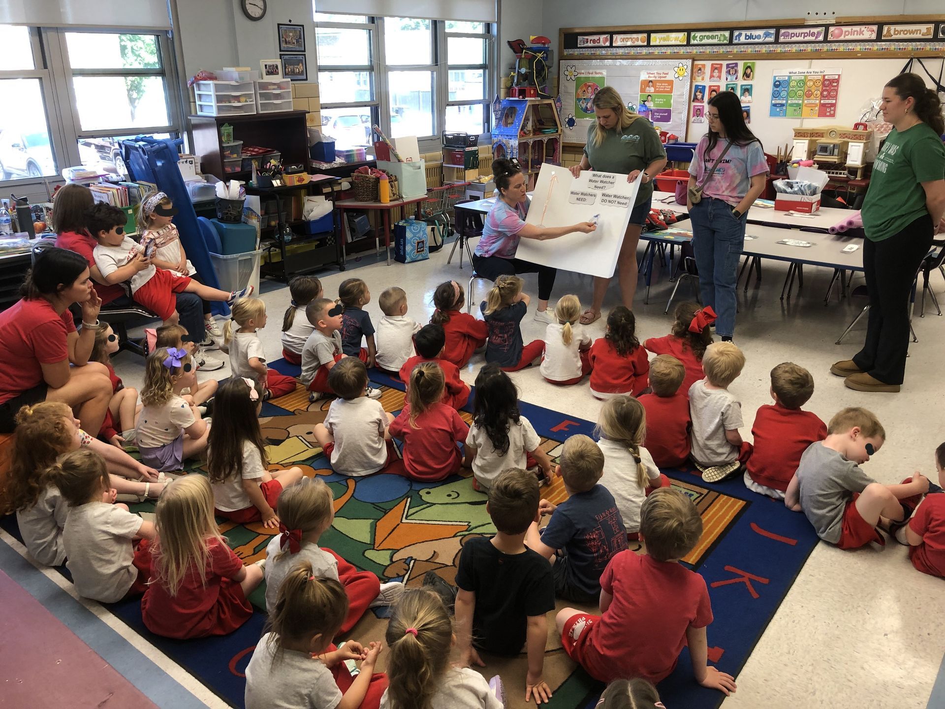 Classroom story time with a teacher reading to children seated on a colorful rug