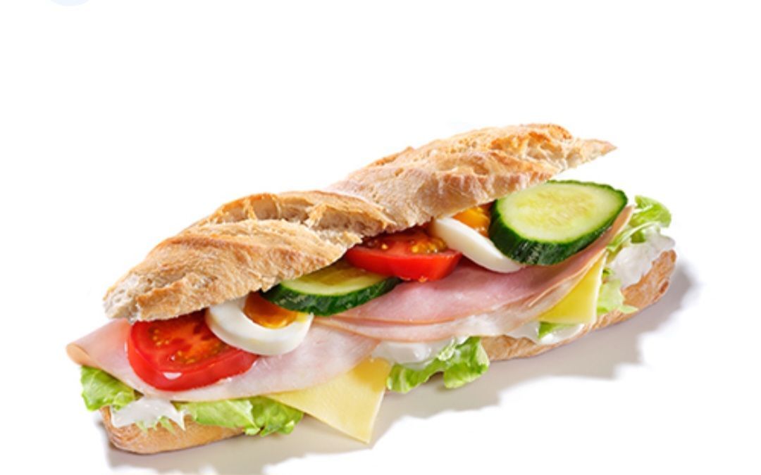 Sandwich met ham, ei, kaas, tomaat en komkommerschijfjes op een stokbrood.