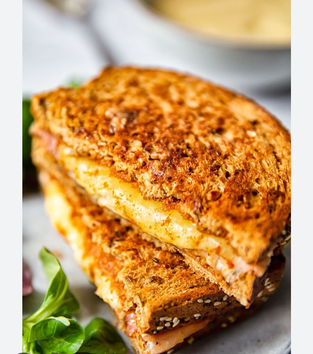 Een gegrilde kaassandwich, rijkelijk belegd, met gesmolten kaas en goudbruin geroosterd brood.