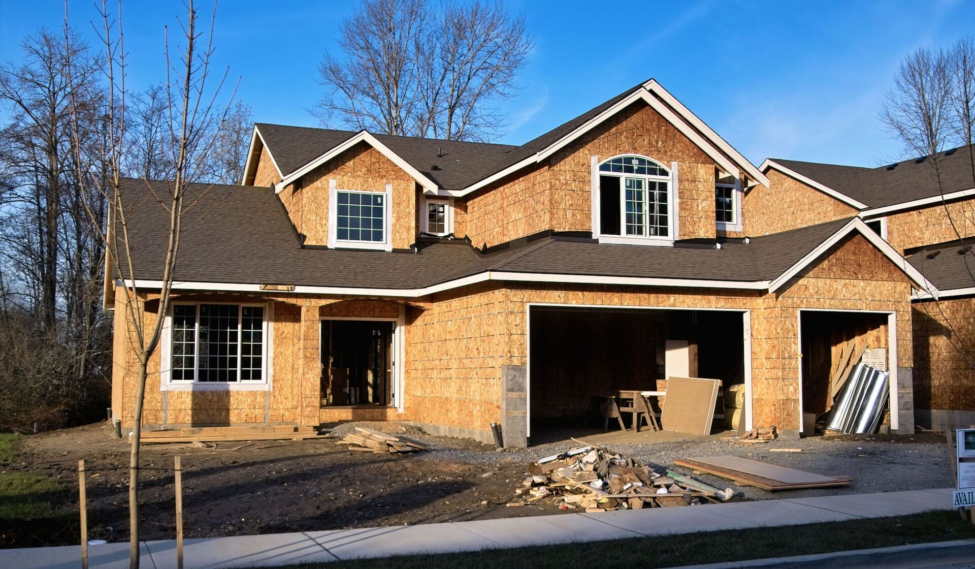 House under construction with wood framing and two-car garage.