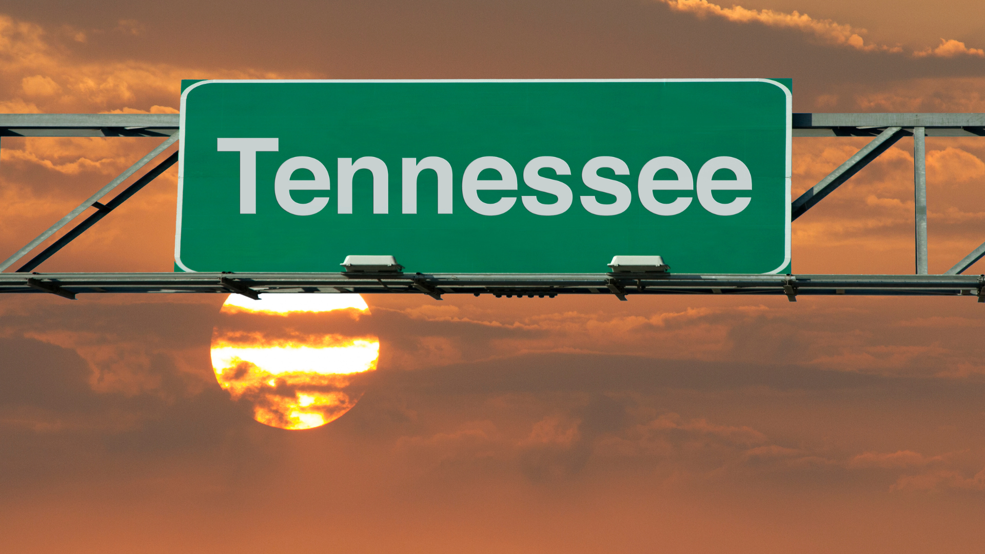 Tennessee highway sign against an orange sunset sky