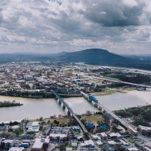 Aerial view of a city with bridges over a river, cloudy sky, and mountains in the distance