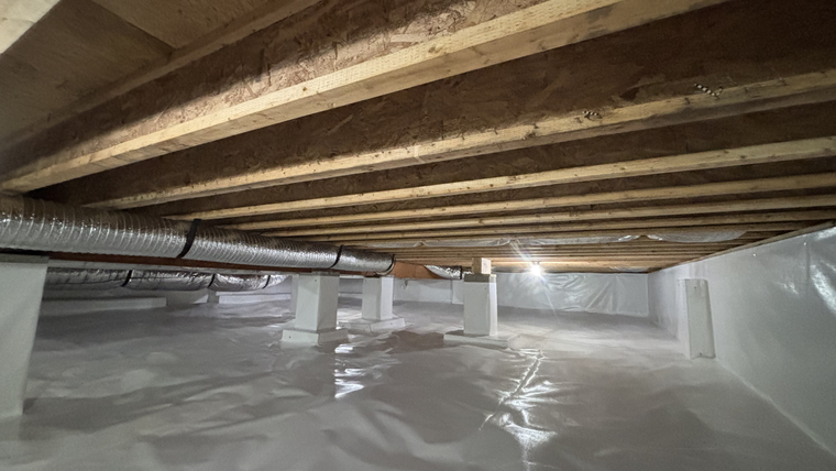 Crawl space with exposed wooden joists, ductwork, and white plastic vapor barrier on the floor and walls