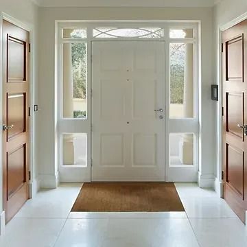 An entrance hall with a white front door flanked by glass panels, two wooden side doors, and white tiled flooring.