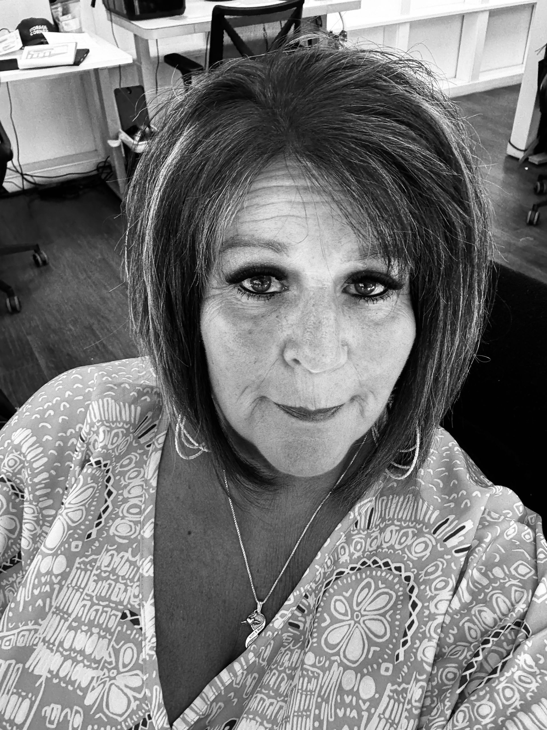 A black and white photo of a woman taking a selfie in an office.