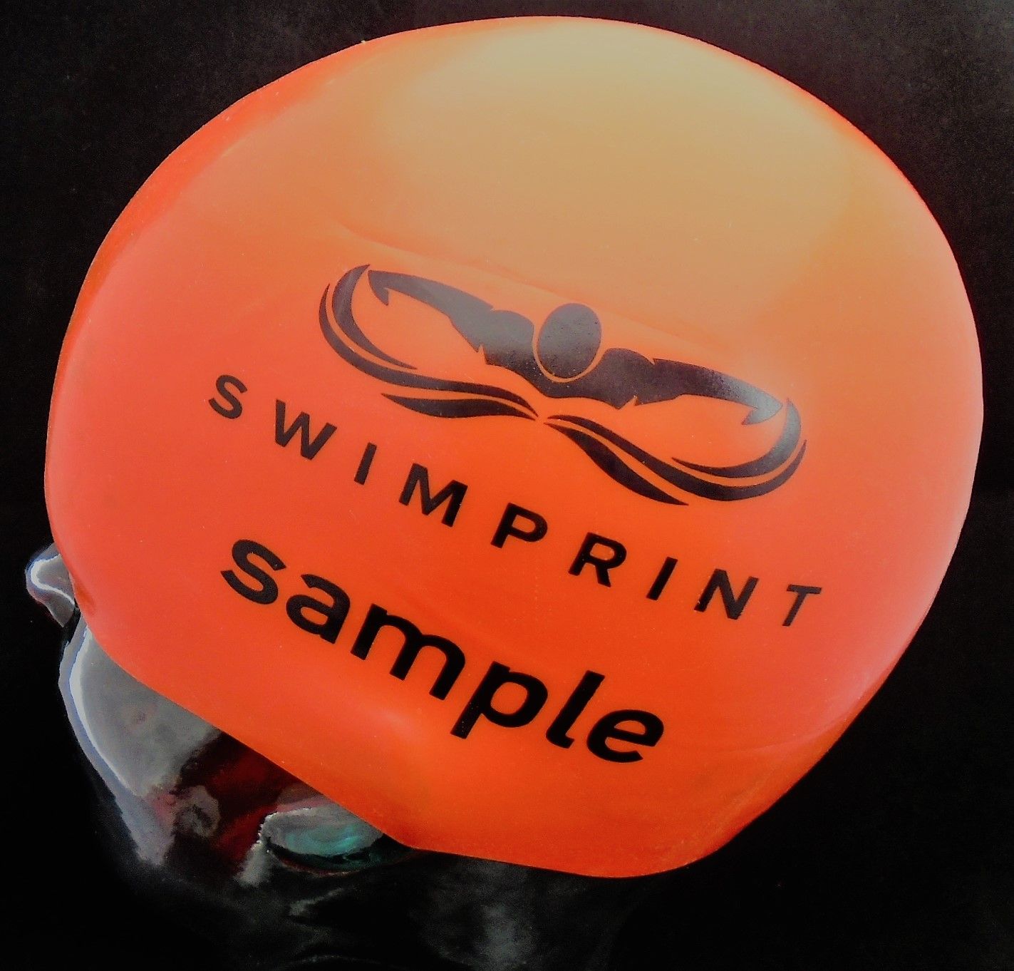 Eine orangefarbene Badekappe mit der Aufschrift „Swimprint Sample“