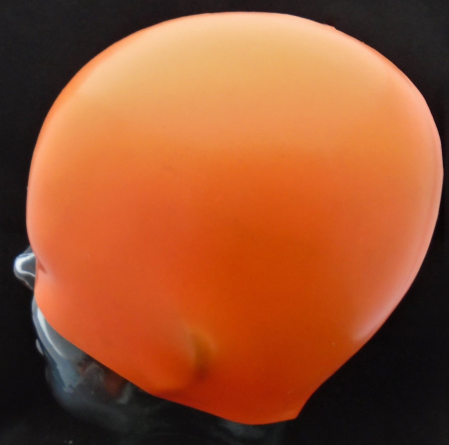 Eine orangefarbene Badekappe ist auf einem Schaufensterpuppenkopf