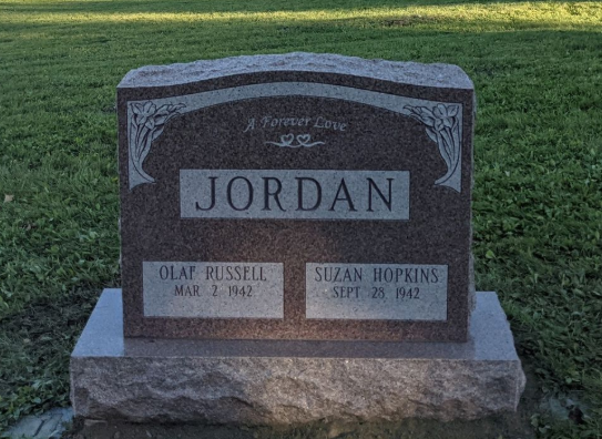 Jordan family gravestone in a grassy cemetery, with two name plaques and a marble headstone.