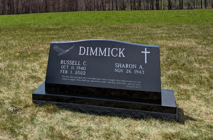 Black granite memorial headstone on grass with the name “DIMMICK” and two inscriptions.