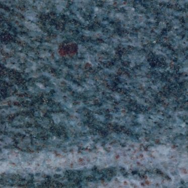 Close-up of a blue-gray textured surface with a faint light streak and small dark spots