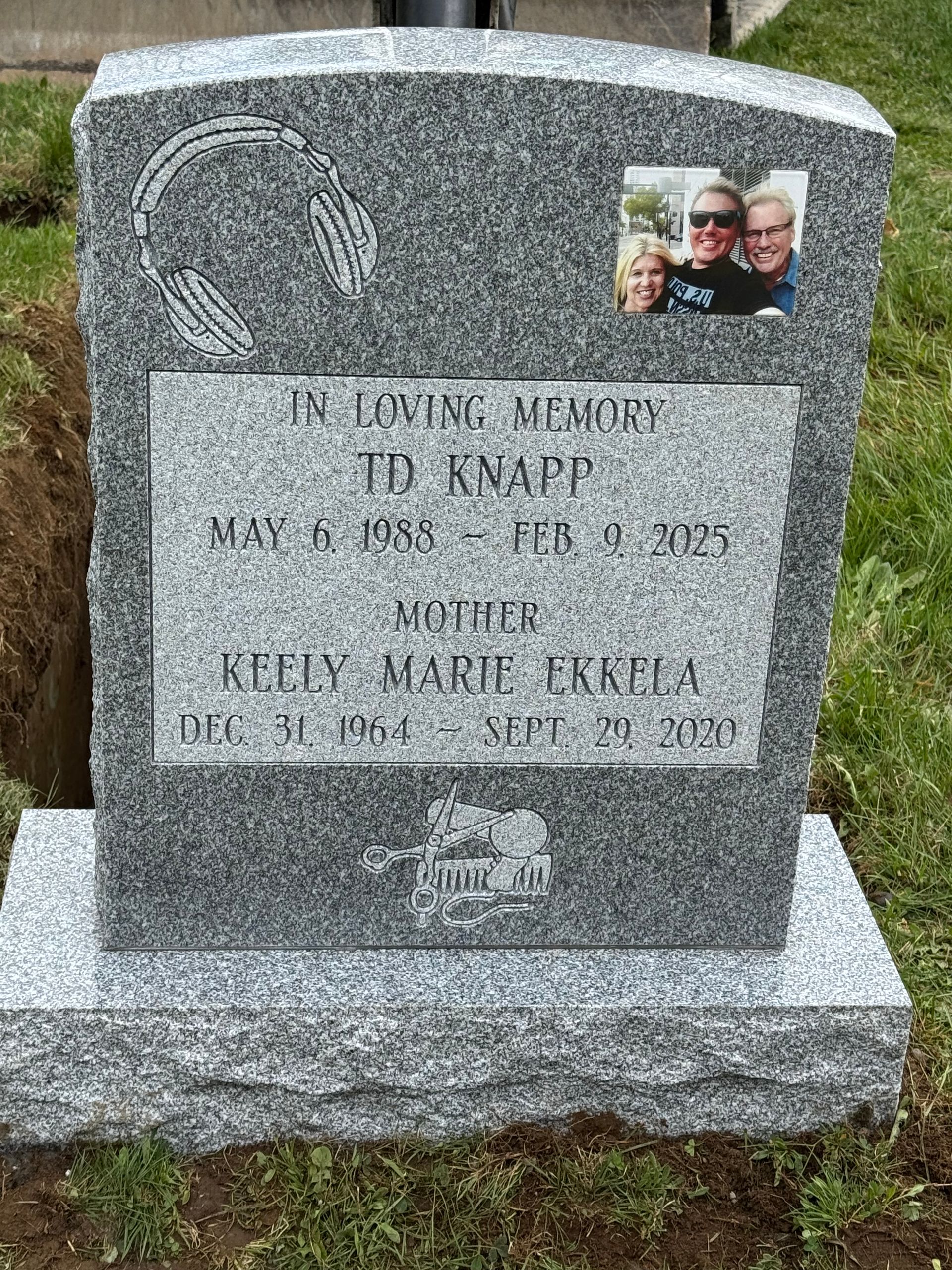 Gray granite memorial headstone with engraved text and a small photo plaque at the top right.