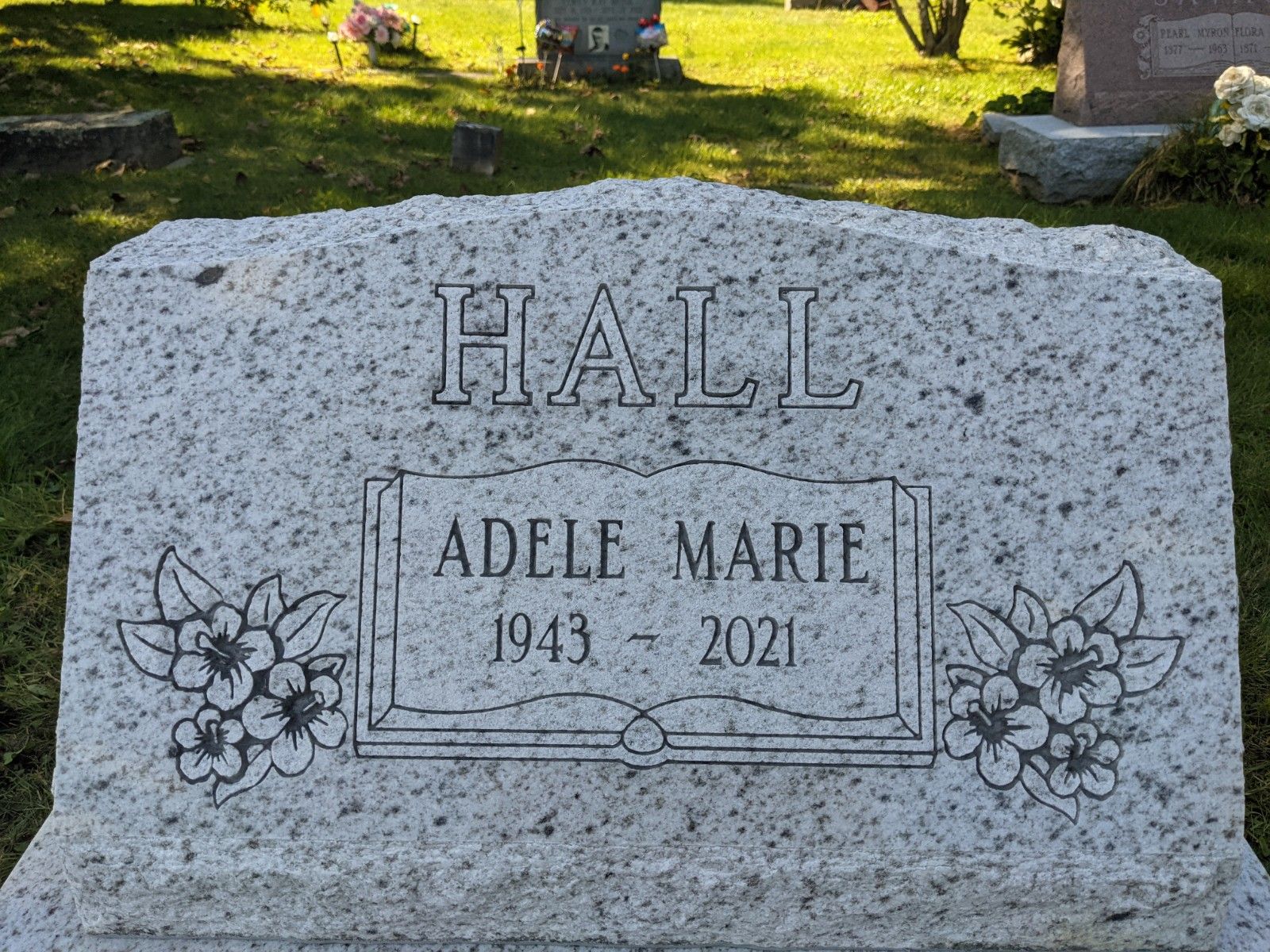 Gravestone with “HALL” and “ADELE MARIE 1943–2024” in a grassy cemetery.