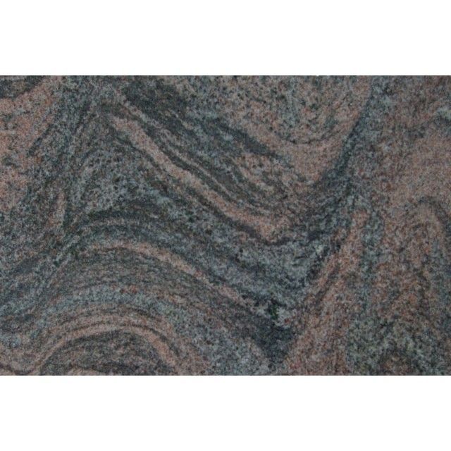 Close-up of layered gray, black, and rust-colored rock with wavy striations