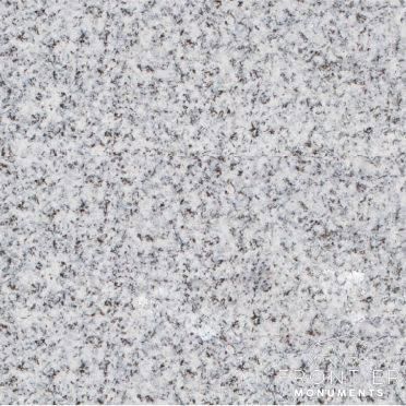 Light gray speckled stone surface with dark flecks and a faint watermark in the lower right