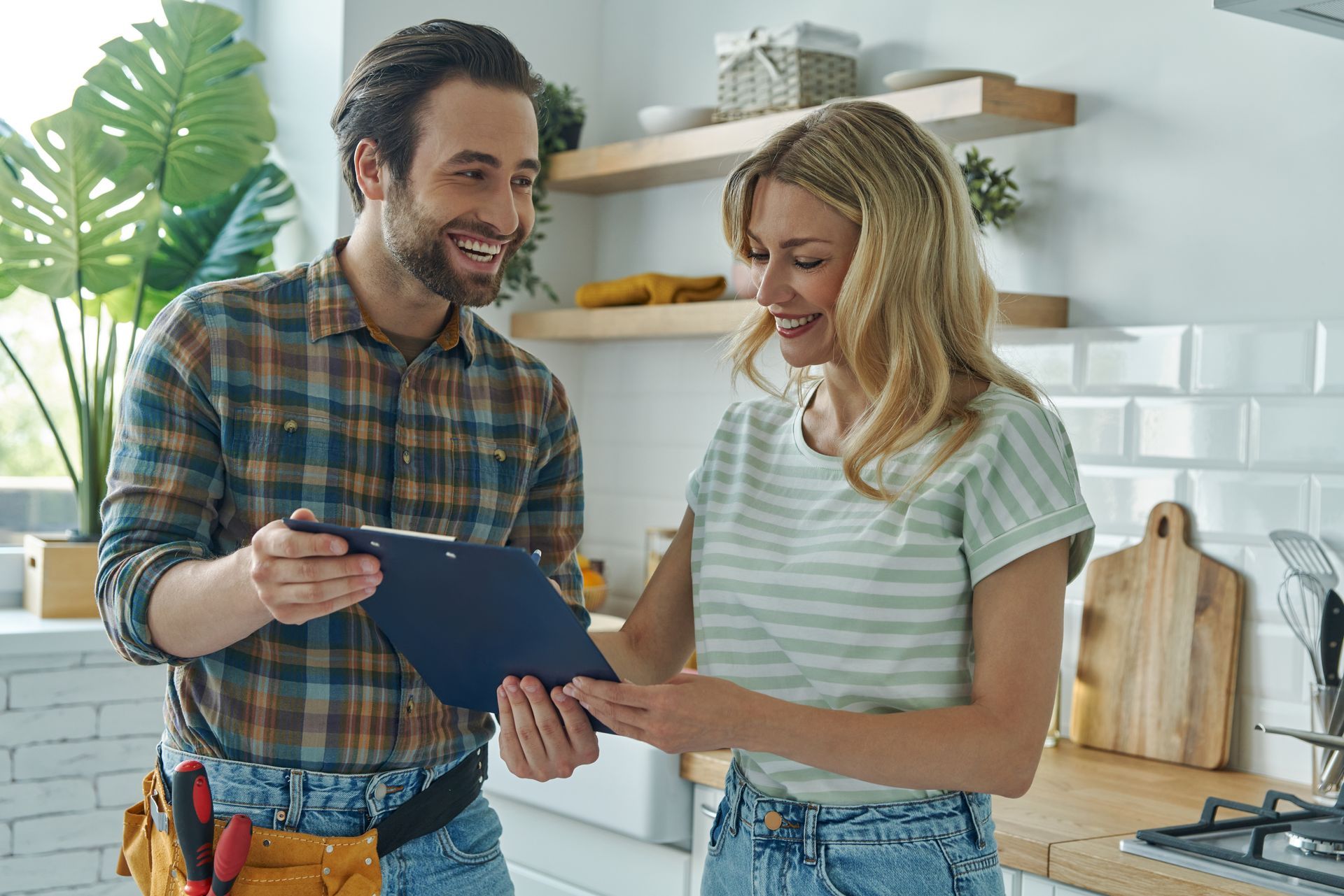Two people smiling and reviewing a clipboard in a bright kitchen