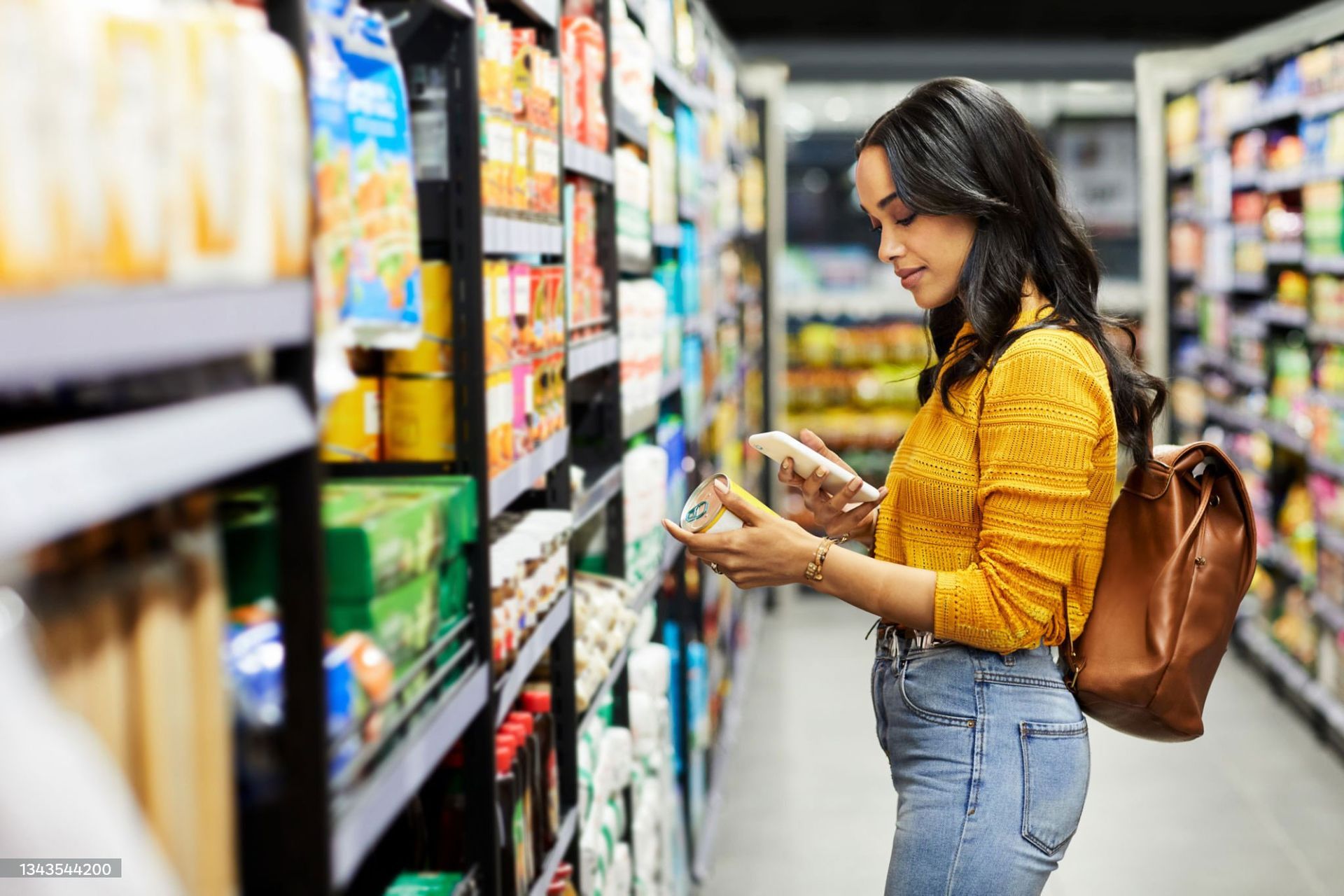 Woman shopping in a grocery aisle, reading a product label while holding a package