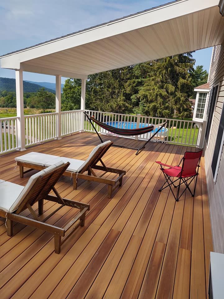 Wooden deck with lounge chairs, a hammock, and a red folding chair, with a mountain view in the background.