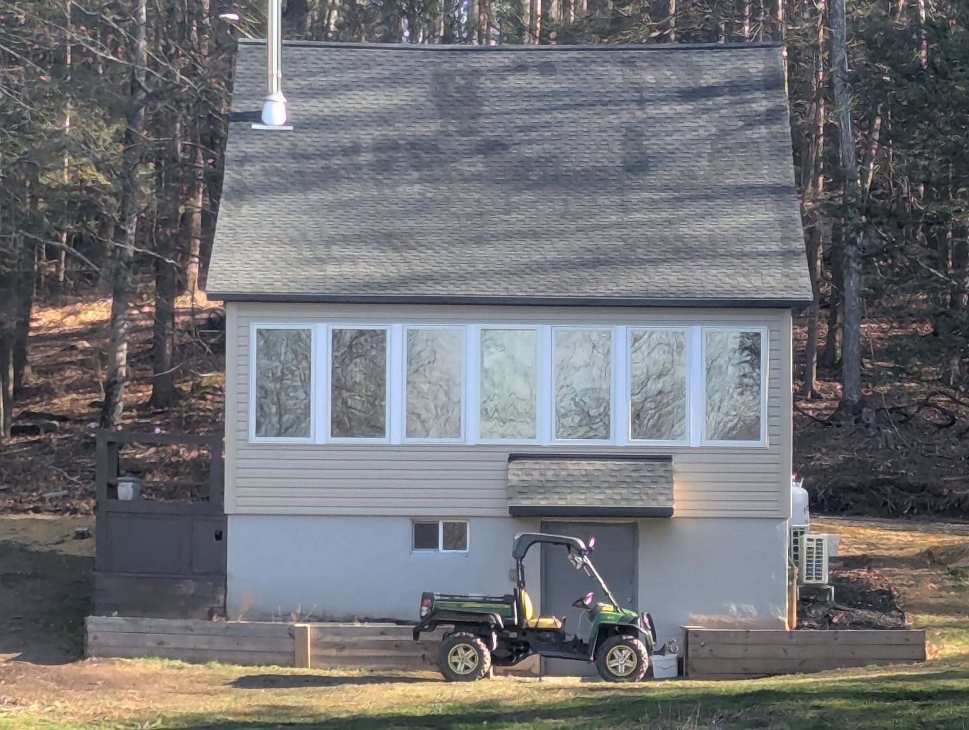 Two-story house with many windows. A green utility vehicle is parked in front.