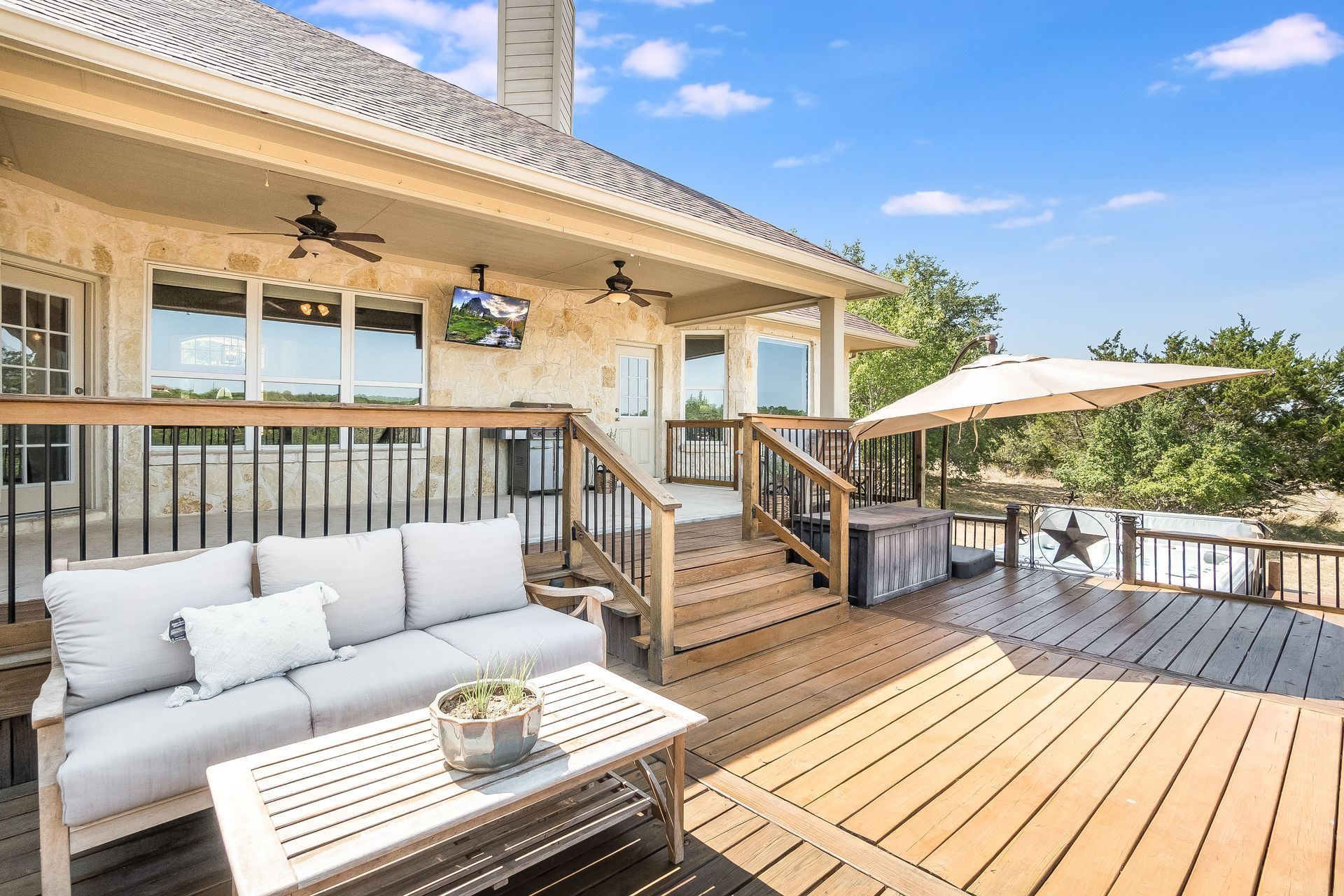 Deck with outdoor seating, stairs, and a partial view of a lake and trees.