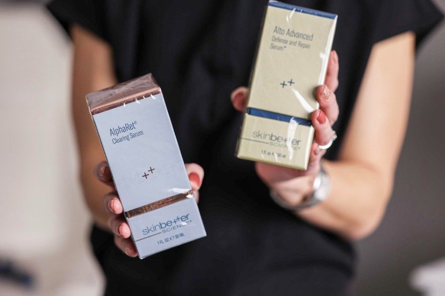 A woman is holding two boxes of perfume in her hands.