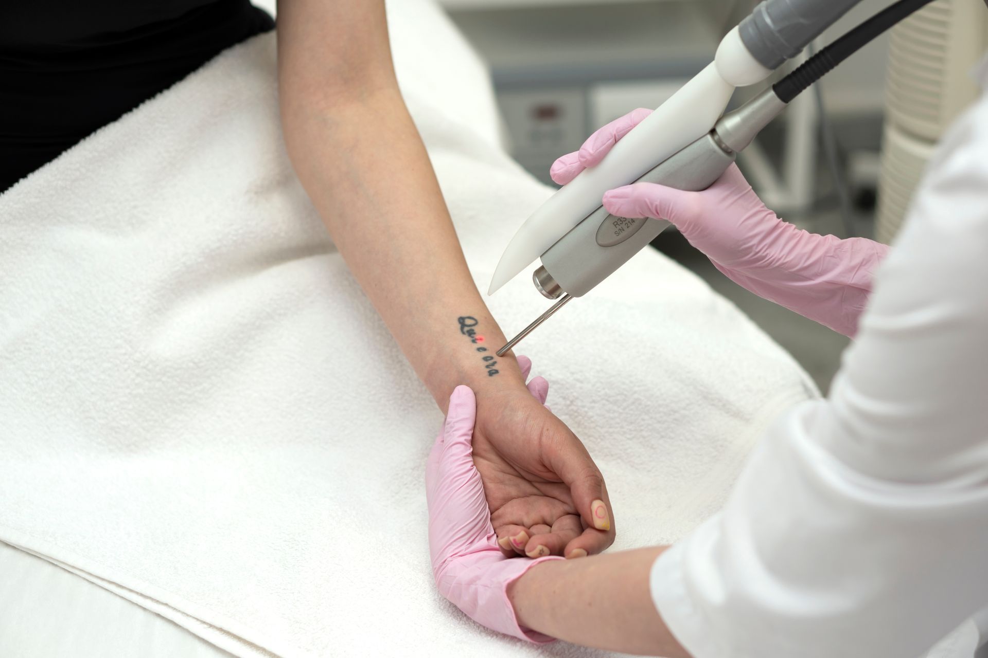 Gloved clinician performing wrist acupuncture on a patient lying on a treatment table