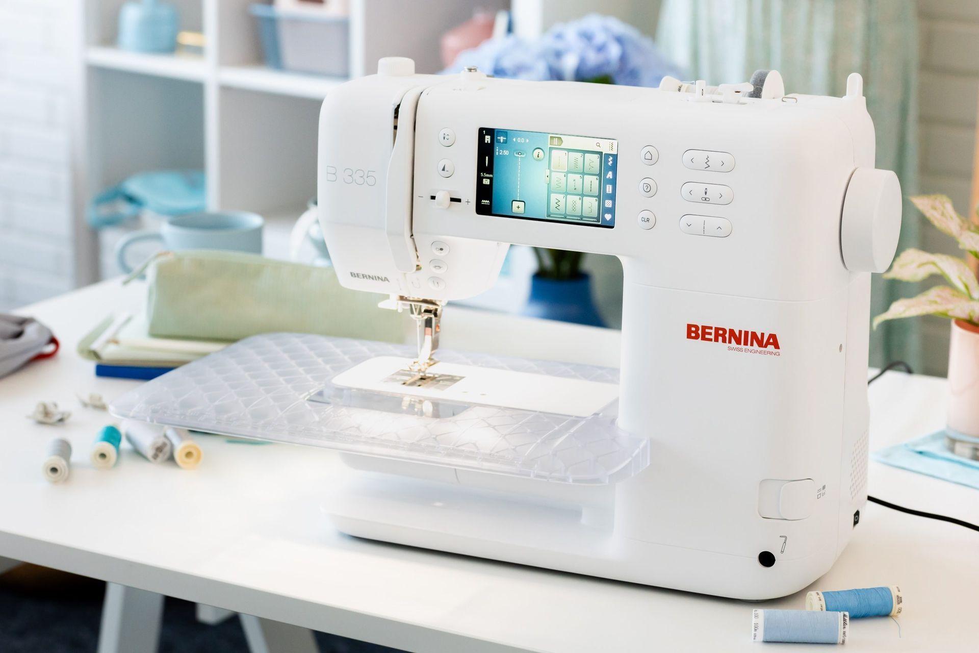 White sewing machine on a bright craft table with fabric and sewing supplies in a home workspace