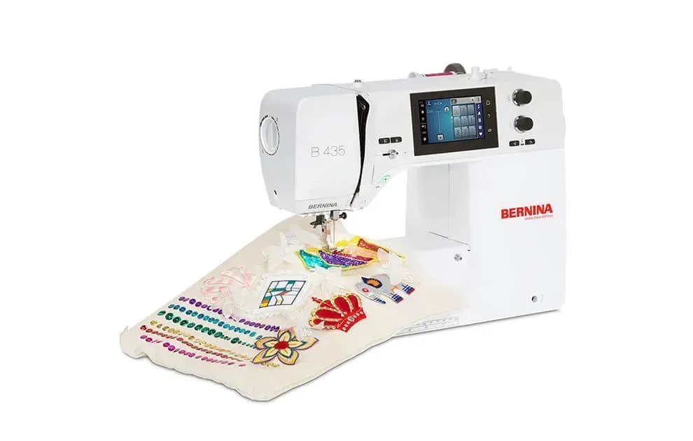 White embroidery machine stitching a colorful fabric design on a flat work surface