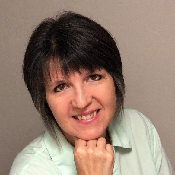 image of female with dark chin length hair wearing a light green shirt and resting her hand on her chin