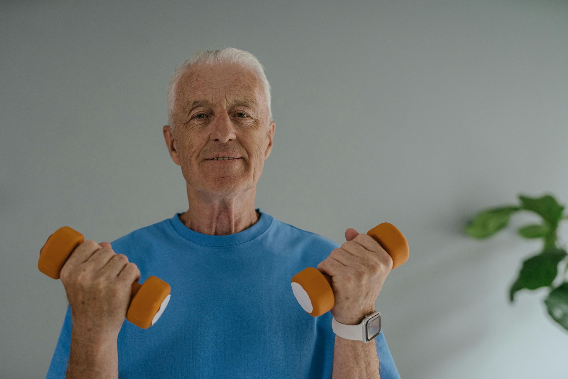 Man with white hair and blue shirt lifting hand weights