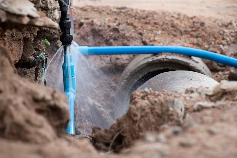 A Pipe Is Bursting in The Dirt and Water Is Coming out Of It — Top To Bottom Plumbing in Garbutt, QLD