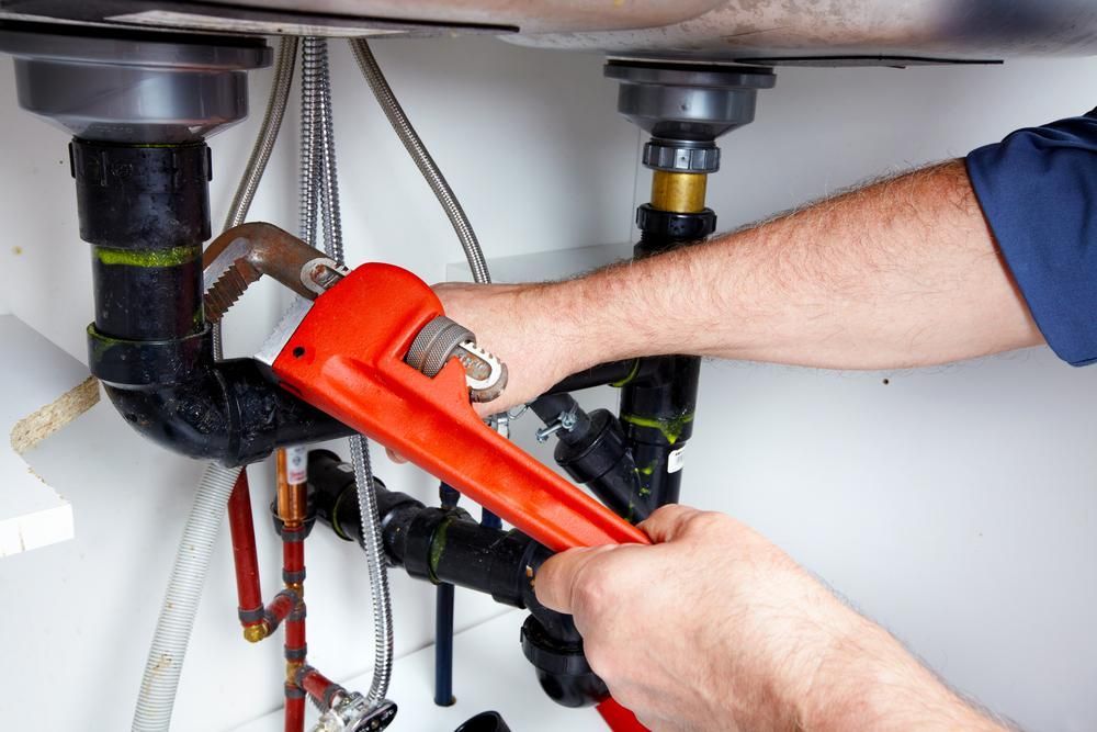 A Plumber Is Fixing a Sink with A Wrench — Top To Bottom Plumbing in Garbutt, QLD