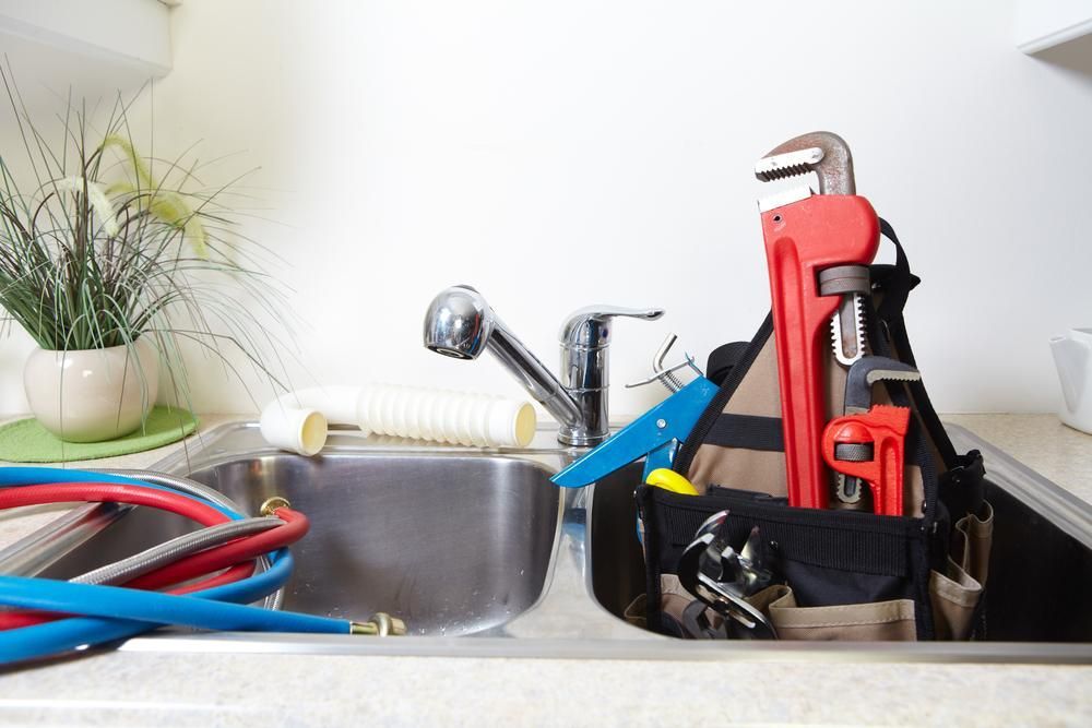 A Kitchen Sink Filled with Tools and A Wrench — Top To Bottom Plumbing in Garbutt, QLD